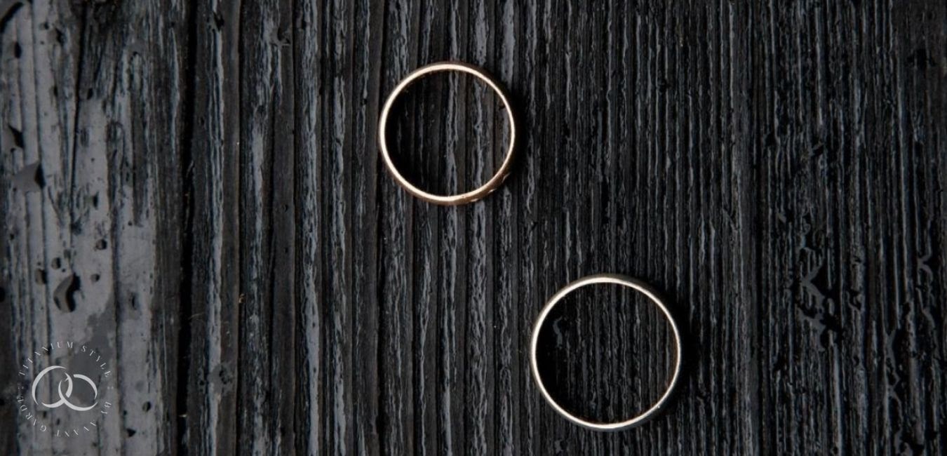 Two titanium wedding rings sitting on a dark wood background