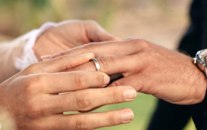 woman putting on men’s titanium wedding band groom