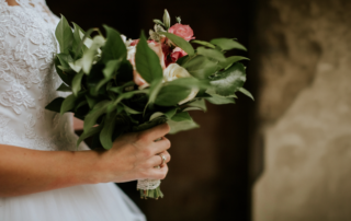 Bride with non-traditional jewelry holding bouquet of flowers.